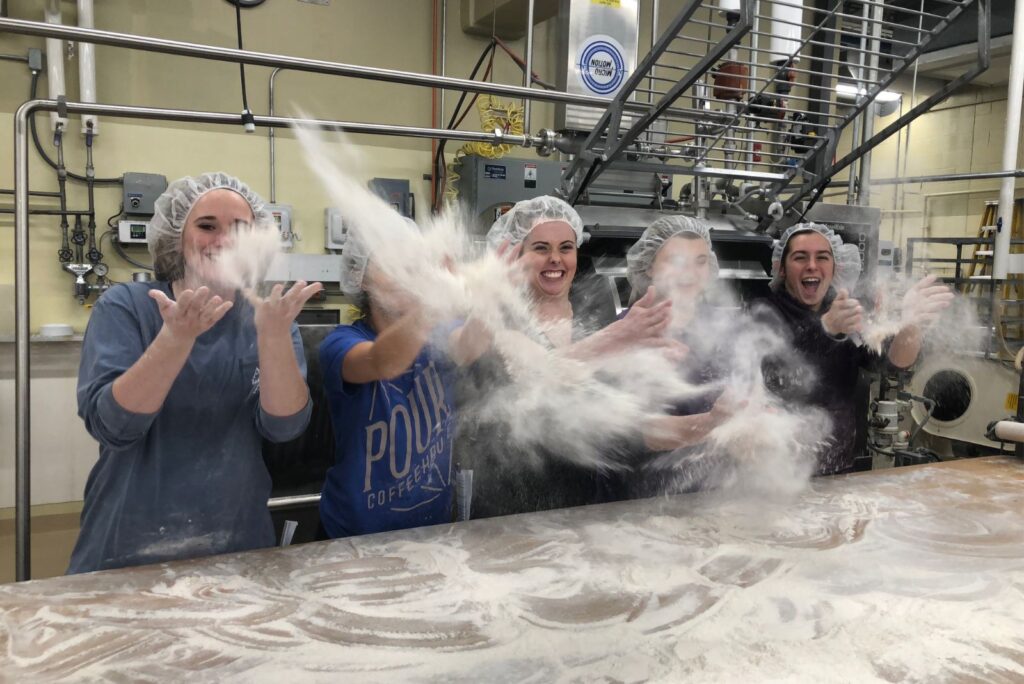 five college-age bakery student throwing flour