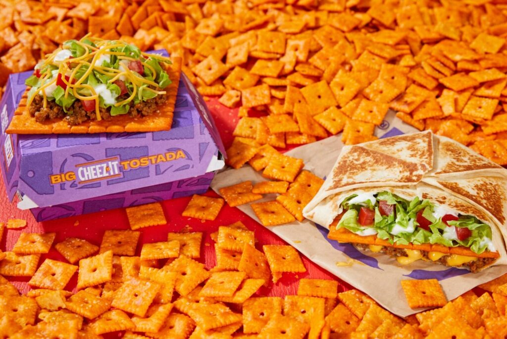 Big Cheez-It Crunchwrap Supreme and Big Cheez-It Tostada on table covered in Cheez-Its.