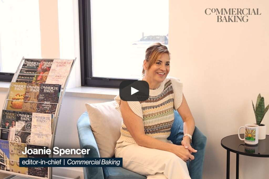 Joanie Spencer sitting in a lounge chair with Commercial Baking magazines in the background.