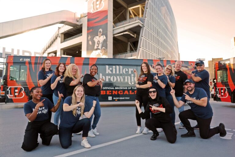 The Killer Brownie Co. team in front of a bus wrapped in tiger print