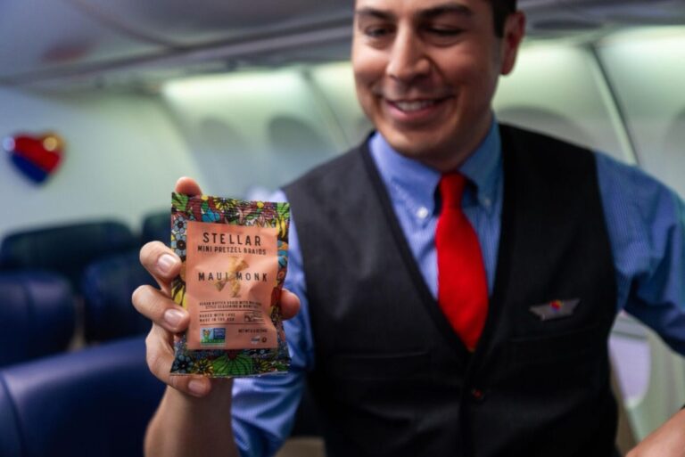 Flight attendant for Southwest Airlines holding Stellar Snacks Mini Pretzel Brads pack