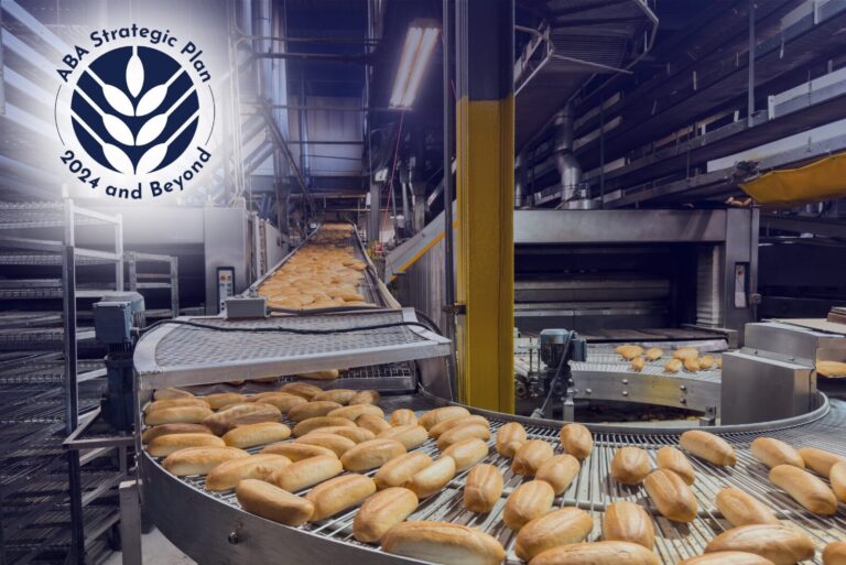 Bread coming off commercial baking line with ABA strategic plan logo in top left corner.