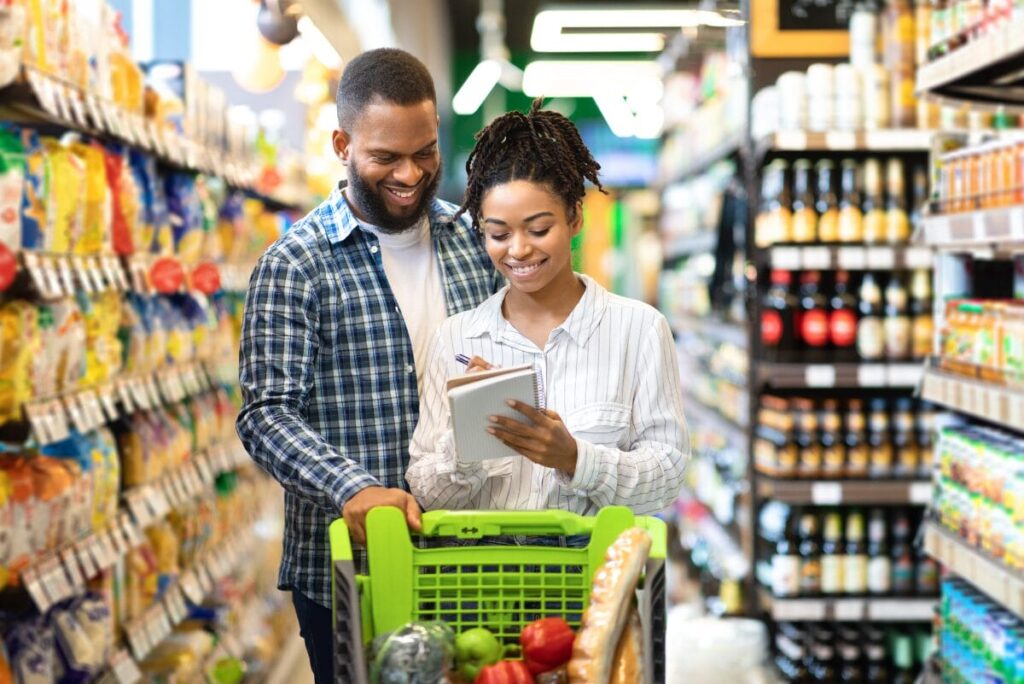 Couple grocery shopping in aisle with cart.