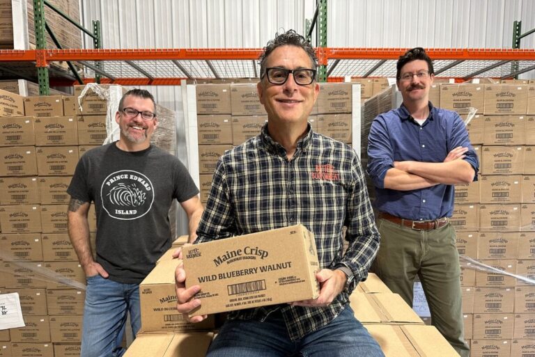 Lewis Goldstein, Joshua Wright, and Chad Pitre in the Maine Crisp warehouse holding boxes of product.