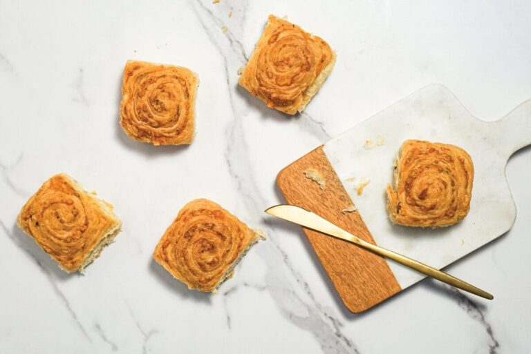 Hero Bread Cheese and Herb Croissant Rolls on white marble countertop and cutting board with gold butterknife