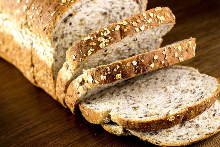 sliced loaf of whole grain bread on dark wood table