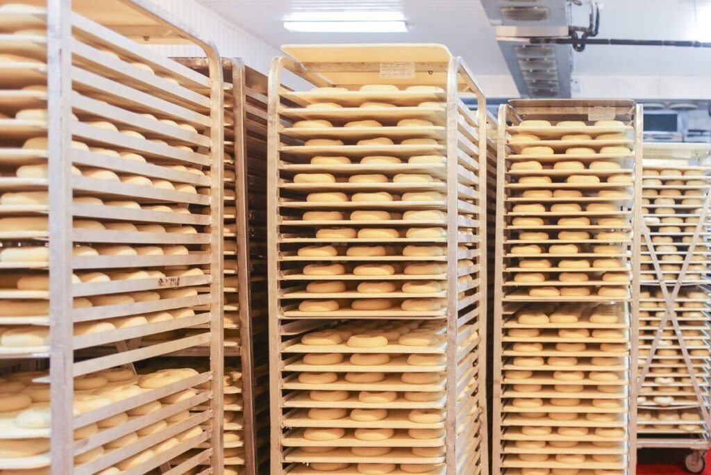 Racks of bagels proofing at Just Bagels in Bronx, NY