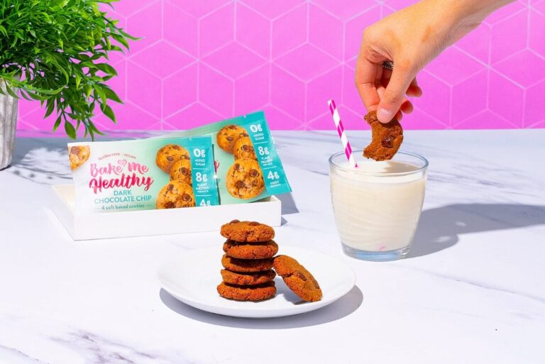 Plate of cookies on table with a glass of milk and package of Bake Me Healthy's cookies.