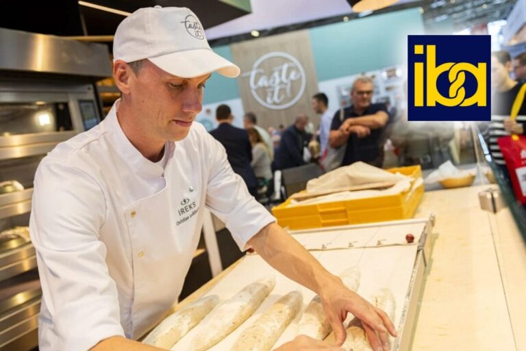 Artisan baker wearing white rolling dough on counter at iba