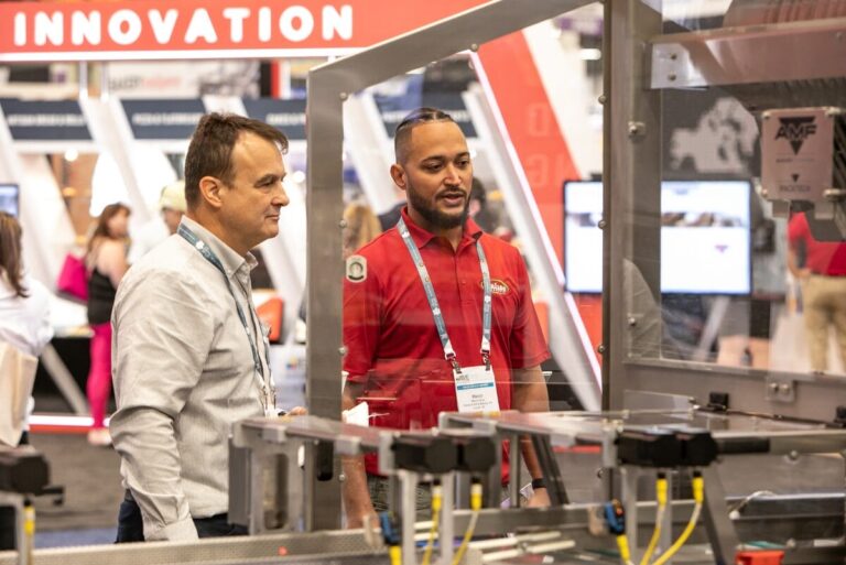 Two men looking at equipment on display at IBIE 2022