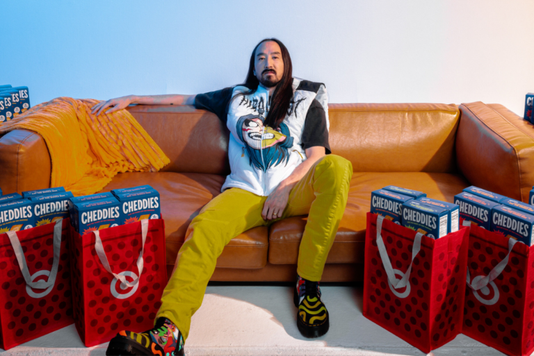 Steve Aoki on couch surrounded by Target bags filled with Cheddies boxes