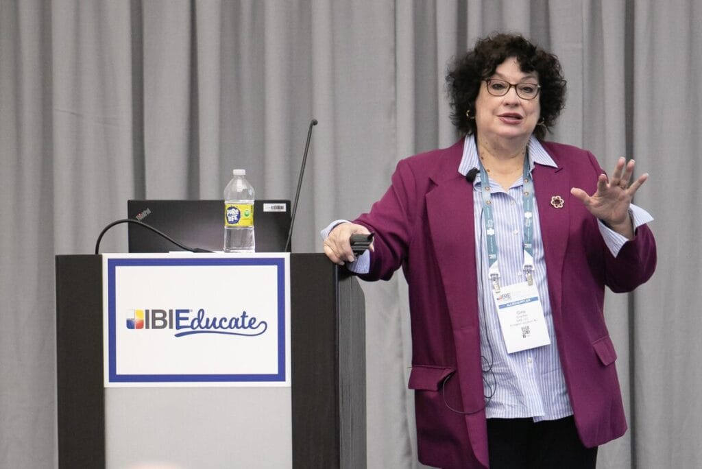 Woman in purple blazer and blue shirt presenting an IBIEducate session at IBIE 2022