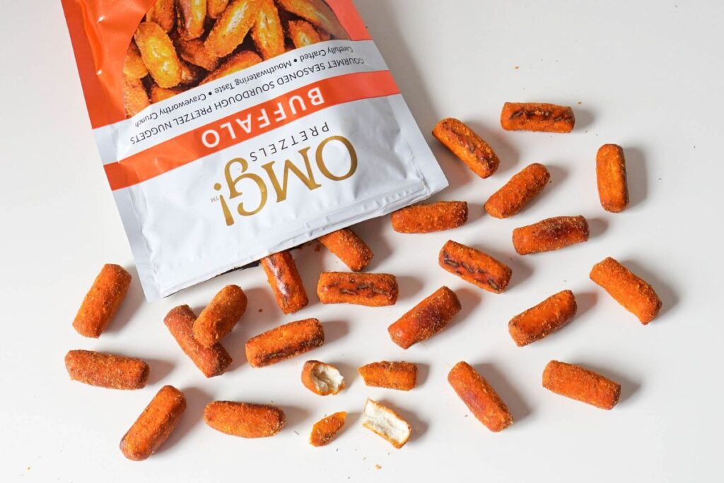Open bag of Buffalo flavor OMG! Pretzels spilling on white surface