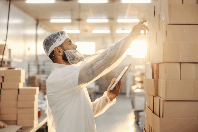 Person checking lot codes on boxes in a warehouse.