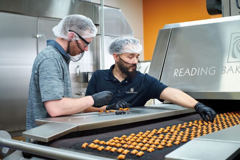 Two Reading Bakery Systems employees evaluating pretzels on equipment