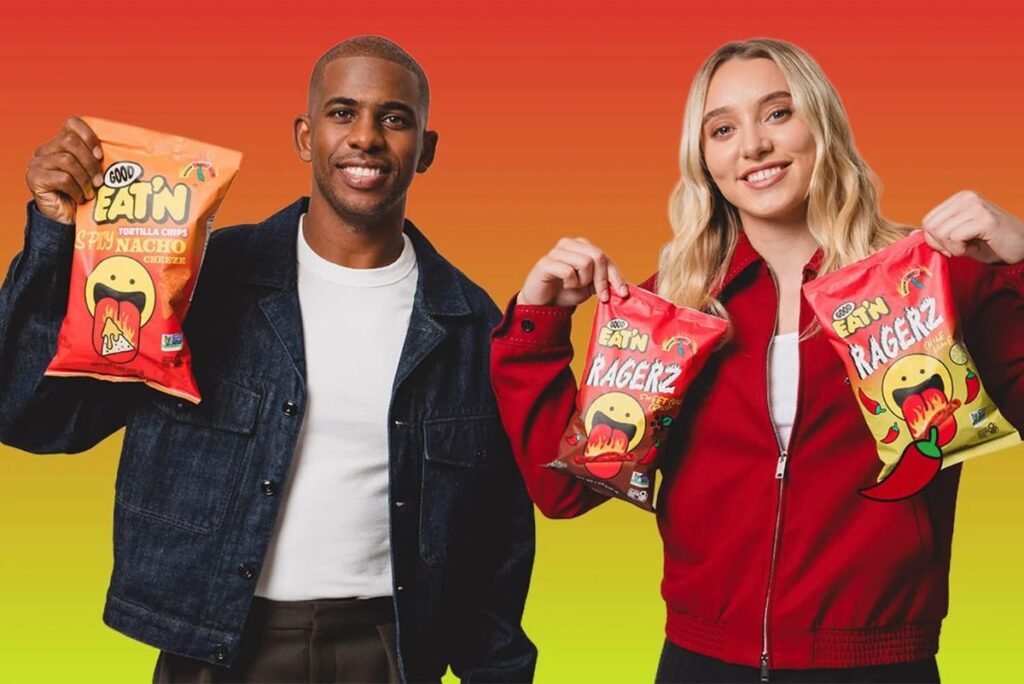 Chris Paul (left) and Paige Bueckets holding Good Eat'n snacks with red-green background