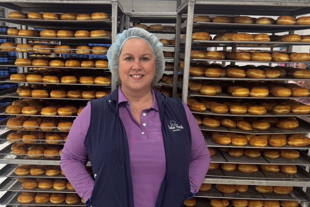 Brandy Lee McNamee, president and CEO of Bake Fresh, standing before a rack of donuts