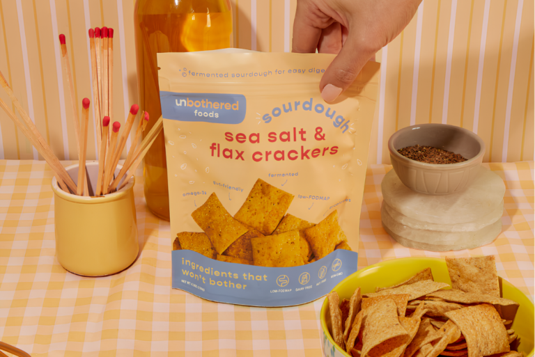Hand grabbing top of bag of Unbothered Foods crackers