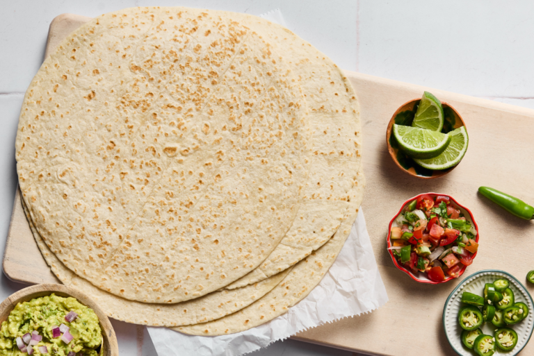Hero Tortilla Burrito on counter with bowls of limes and pico de gallo