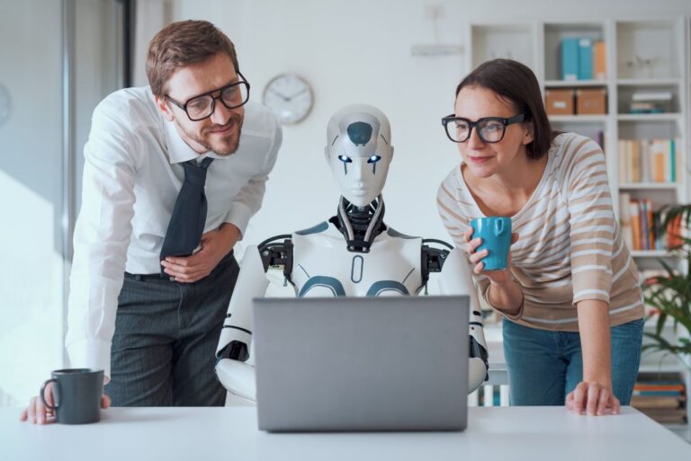 two business people watching a robot work on a laptop