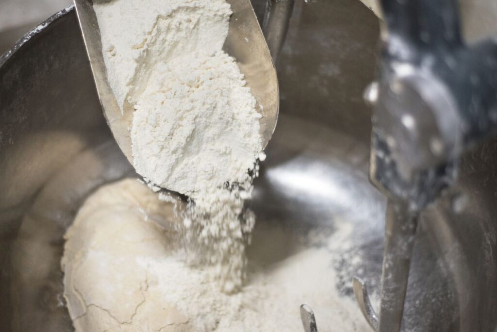scoop of flour going into mixing bowl