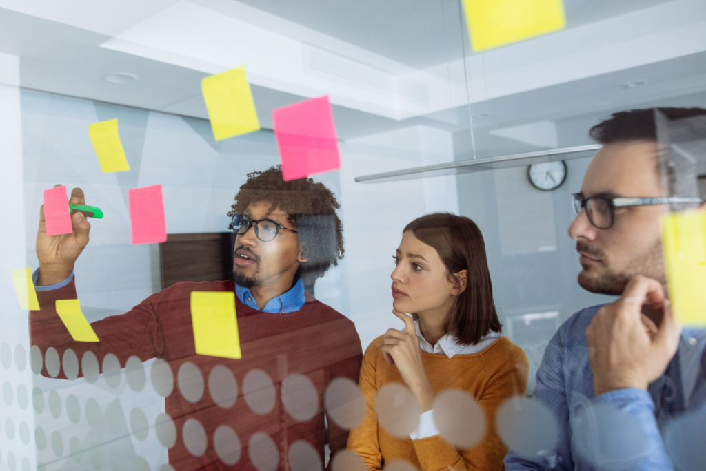People behind glass wall with colorful sticky notes