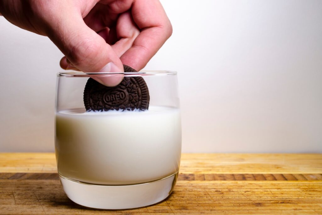 Person dunking Oreo in glass of milk