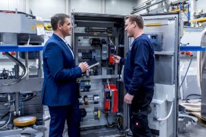 two men surveying a piece of bakery equipment